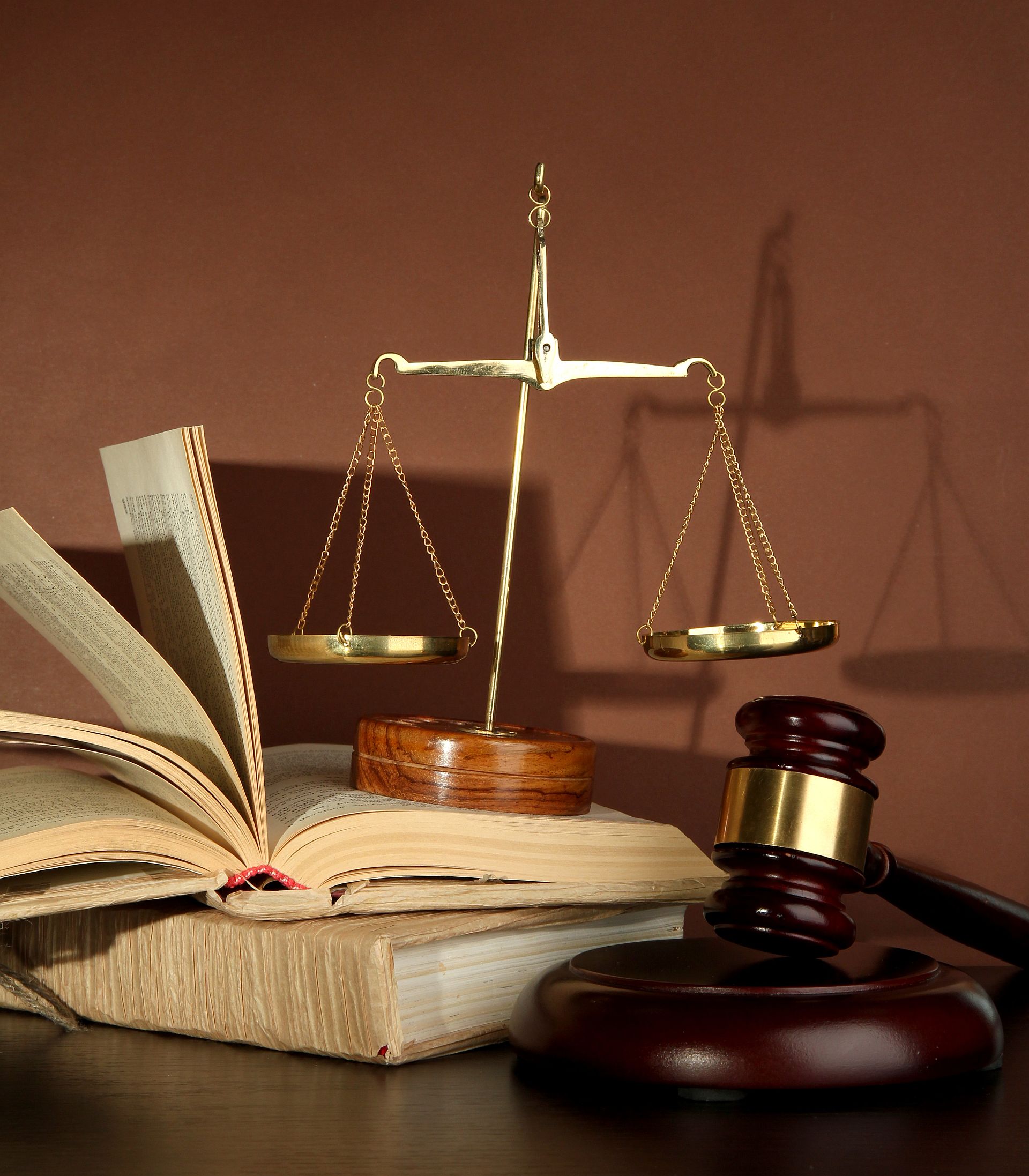 Golden scales of justice, gavel and books on brown background